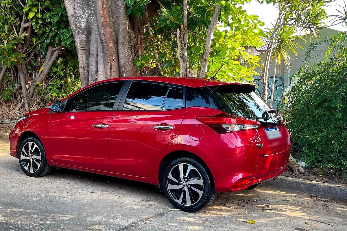 Un Toyota Yaris rojo recién lavado, con la chapa brillando bajo el sol