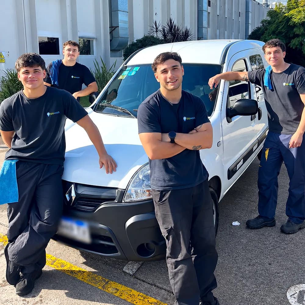 Los cuatro biowashers con la remera negra de la marca, posando alrededor de la camioneta blanca de BioWash en la playa de una planta industrial